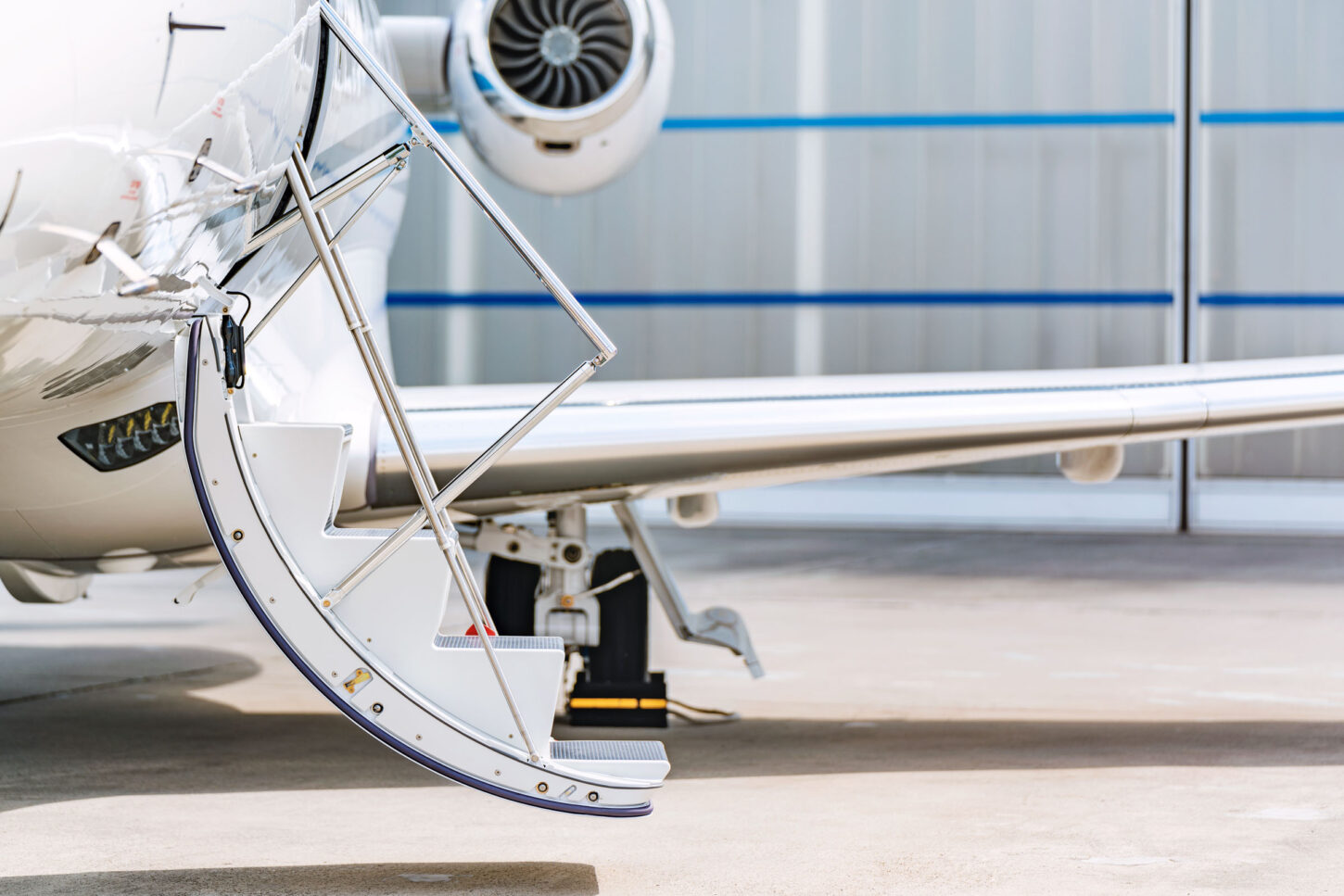 close up on the open staircase of a parked aircraft in front of the hangar