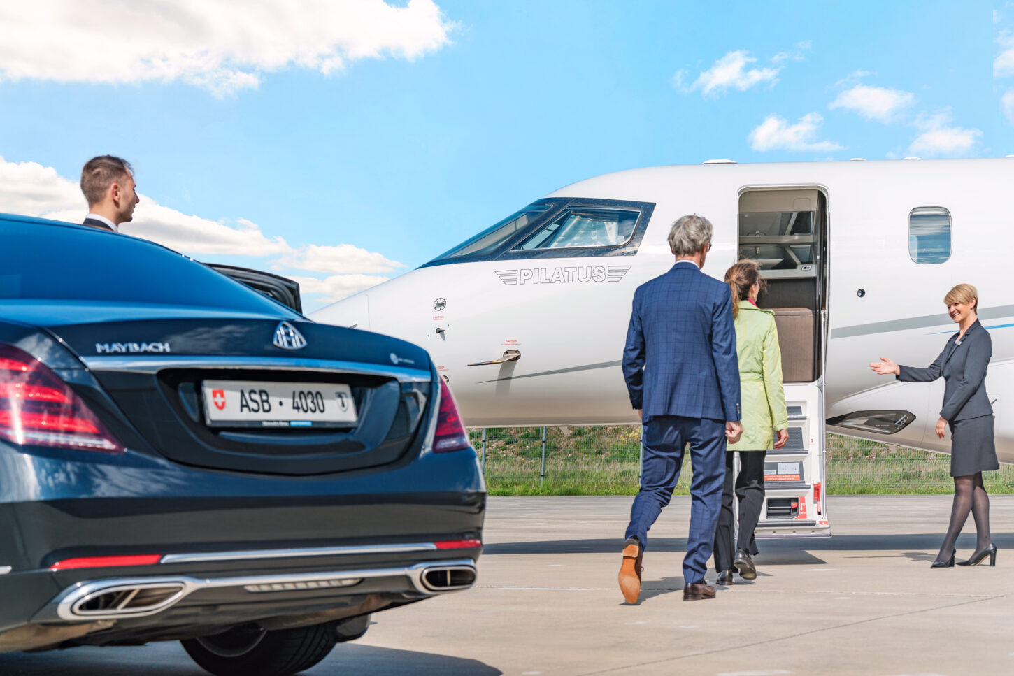 A couple is greeted in a friendly manner by the flight attendant as they are about to transfer from the limousine to the aircraft.
